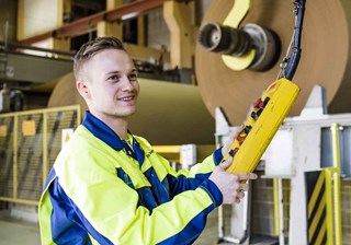 Un homme souriant tient à la main un boîtier pour contrôler les machines à l'usine