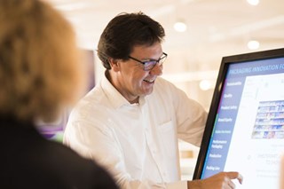 Un homme fait une présentation d'emballage à une dame à l'aide d'un écran à l'Experience Centre