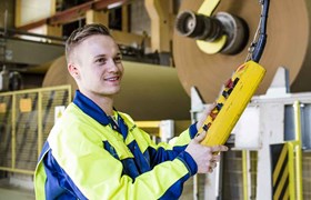 Un homme souriant tient à la main un boîtier pour contrôler les machines à l'usine